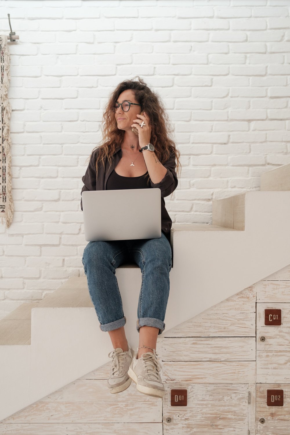 Woman Calling on Smartphone and Using Laptop on the Stairs